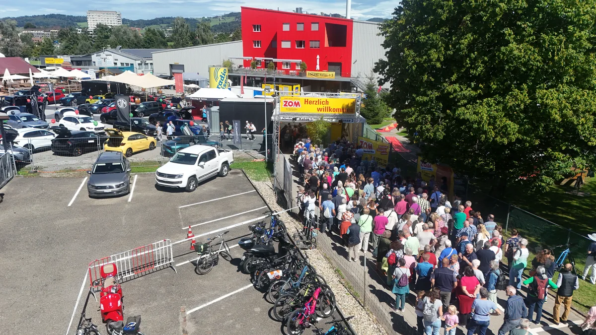 Anstehen, bis es losgeht: Die Menschen aus der Region freuen sich auf die Messe. Ein Luftbild zeigt Menschen in einer Warteschlange. An deren Ende ist ein Gerüst mit einem gelben Transparent zu sehen. Darauf steht «ZOM: Herzlich willkommen».
